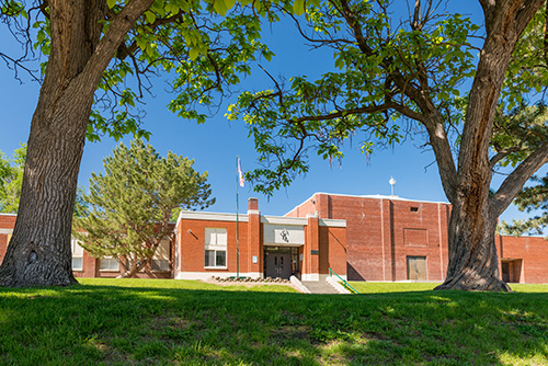 Adrian High School is a brick building with grassy area and trees in front.