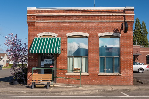1 story brick building with a green an awning over the front door.