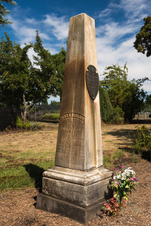 Obelisk style monument with spring flowers in a vase at the base.