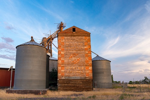 A tall rectangular building with three silos beside it. 