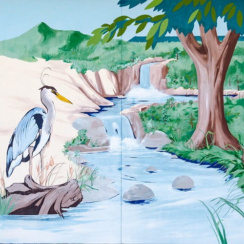 A mural of a blue heron standing by a stream with trees and grass on the bank.