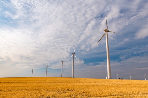 Five wind turbines on a dry grass hill.