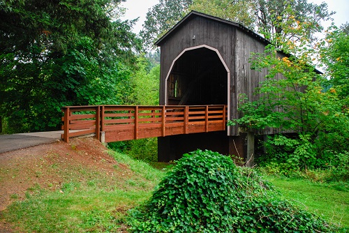 Built 1925 Pass Creek Bridge is covered with cedar siding & includes hand-hewn timbers, likely repurposed from earlier bridge.