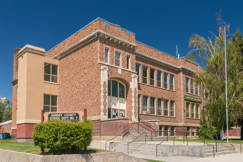 Three story brick building with a sign outside for Harney County School District number 3.