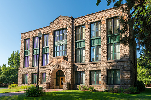 Three story brick building with a grassy lawn in front.