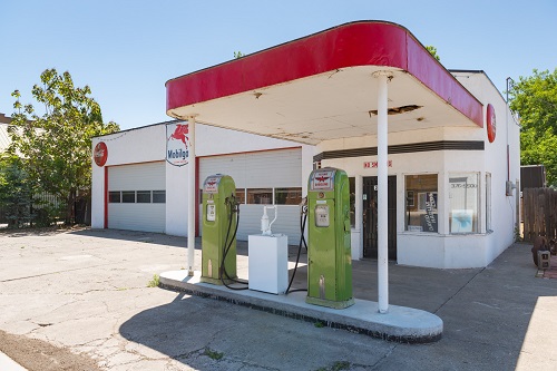 Two Flying A Gasoline pumps on a cement island outside a vintage gas station.