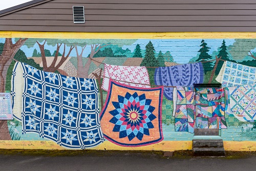 Mural of colorful quilts on the side of a building.