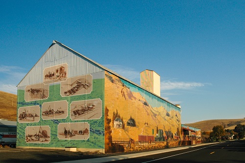 Murals on the side of a building depict farming, agriculture and old west landscape of Morrow County.