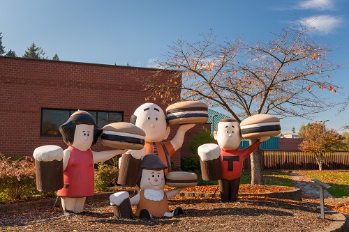 Out door art A&W Burger Family statues are 4 statues of smiling family members. Each holds a sandwich and a mug of root beer.