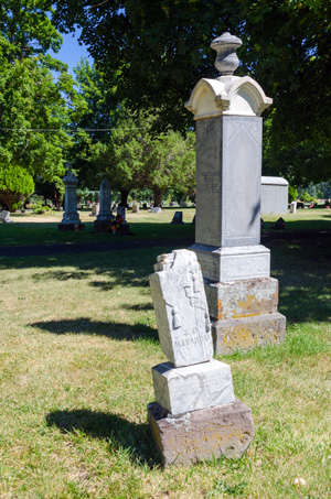 Stone pillars, one slightly askew, stand marking graves in a cemetery in Island City.