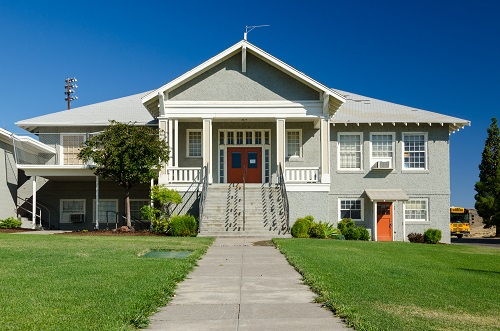 2-story school house with a stairway leading to the front double doors on the 2nd floor. 
