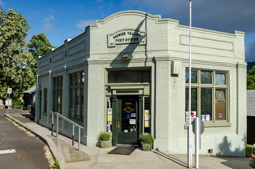 1-story, brick building with front door set at angle to corner sidewalk. Sign over top reads "Mosier Valley Post Office 1914."