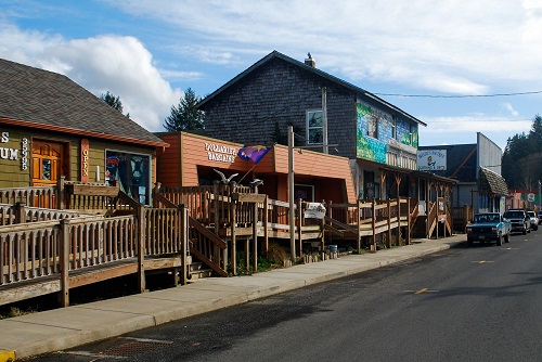 Street view of tourist shops on 7th avenue. Wooden ramps with railings lead up to boardwalk in front of shops.