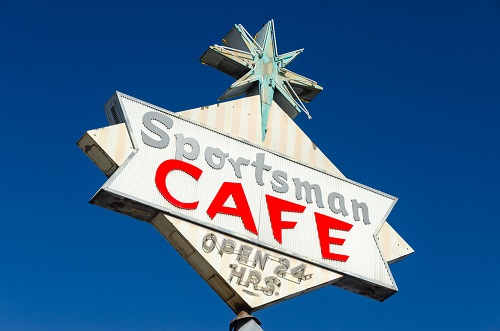 Las Vegas style sign with star on top, a banner shape inside a diamond shape with the words: Sportsman Cafe Open 24 hours.