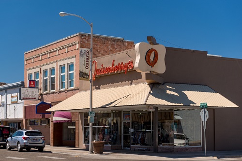 Street view of commercial businesses in downtown ontario. The corner store has a sign with a large letter Q over the awning.