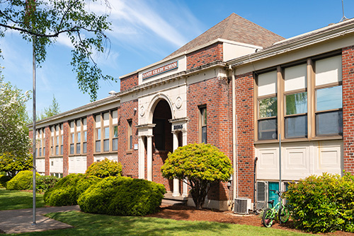 A traditional brick school building with a gabled roof and arched entrance. The name Thomas Jefferson High School is displayed above the entrance in capital letters.