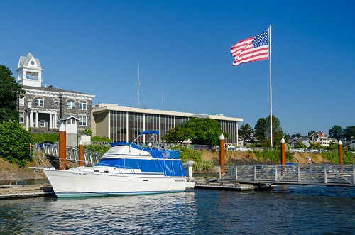 A fishing boat floats next to a dock in the Saint Helens marina. A flag flys on a flag pole nearby. 