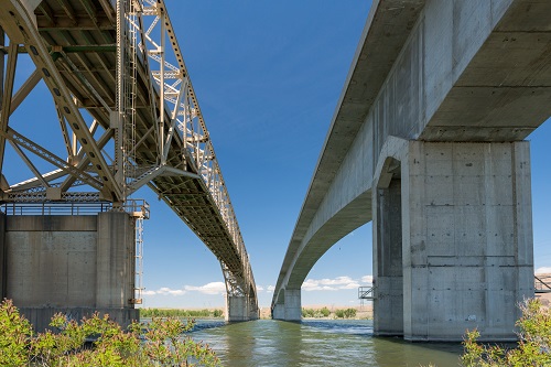 Pair of bridges across the Columbia River. Bridge on right is concrete arch bridge, on left a steel through truss cantilever.