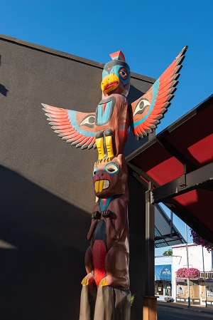 14 foot totem pole depicting a thunderbird sitting on top of a beaver.