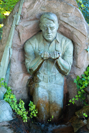 Sculpture of soldier kneeling at stream for water.