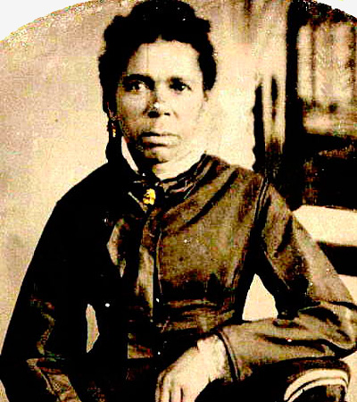 A Black woman, Mary Amanda Mathews, sits for a formal portrait. She wears period clothing typical of the late 19th century, looking directly at the camera with a calm, confident expression.