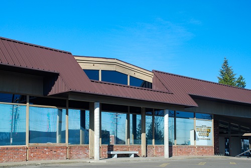 Building Codes Division office – a two‑story mid‑century brick office building with rows of rectangular windows, a centered main entrance under a flat canopy.