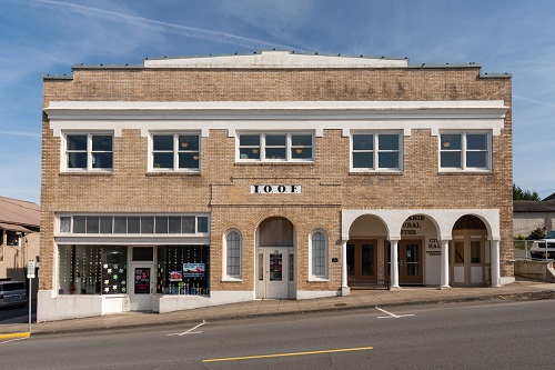 A two-story building of reinforced concrete with a brick facade seated on a hillside street.