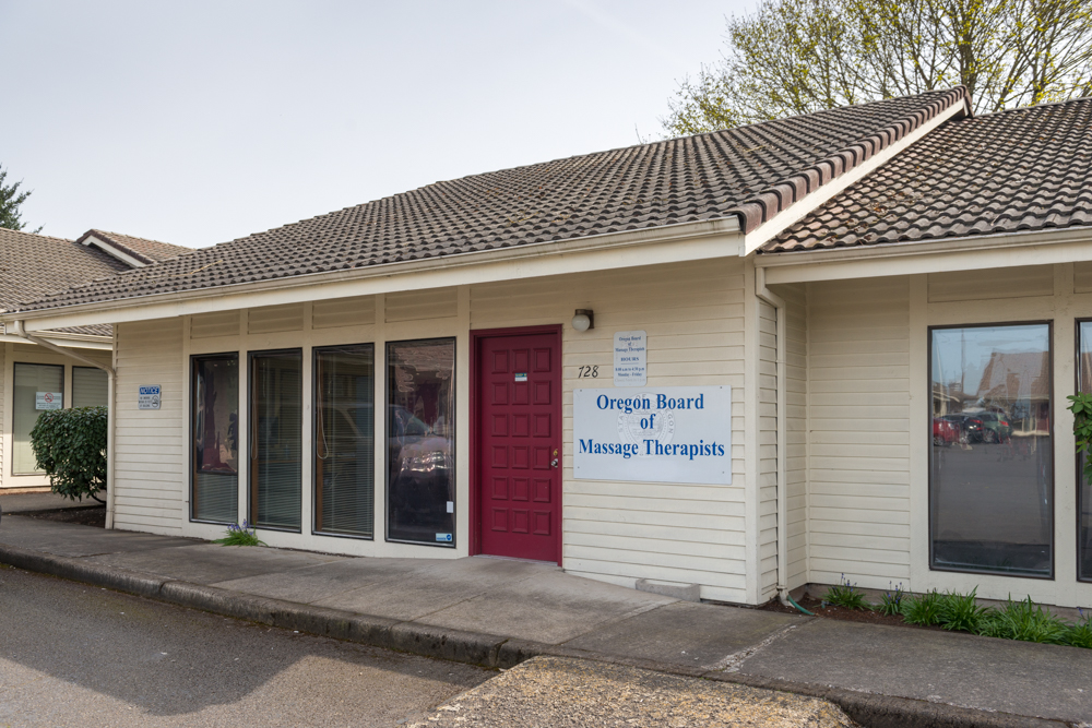 Exterior of the Oregon Board of Massage Therapists office, a single story building with a sidewalk in front and parking places.
