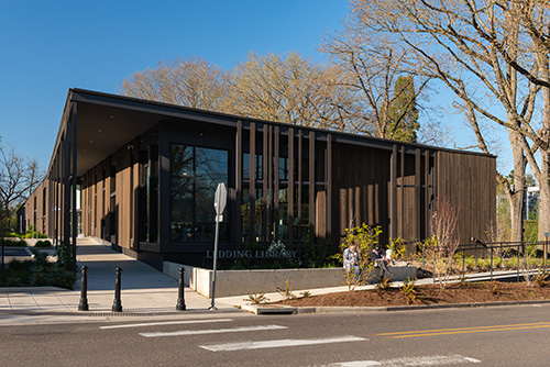 Exterior view of the Ledding Library in Milwaukie, Oregon. The library features a modern design with large glass windows and a welcoming entrance.