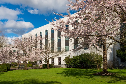 Two‑story white marble Public Service Building in Salem with a flat roof, symmetrical tall windows, and a central entrance, set among landscaped grounds.