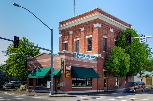 One-story brick building with a 2-story brick building attached. A banner on the side says Springfield Farmers Market.