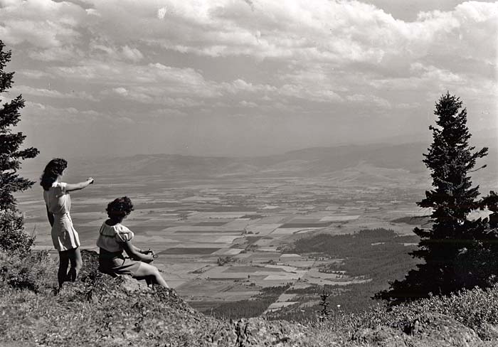 Two women sit on a hillside of Mt. Emily and look out over the Grande Ronde Valley.