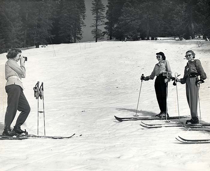 Three female skiers in the Tollgate area. Two women pose while the other takes a photo.