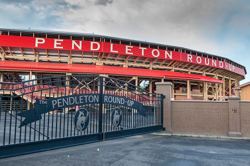Wide gates to the Pendleton Round-Up arena. The stands where people sit are seen behind the gates under a long roof.