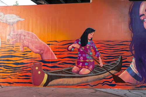 Mural shows a Native American woman paddling a canoe on water.