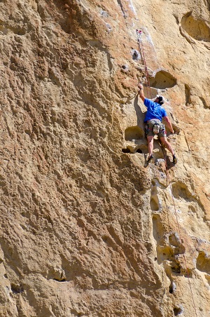 A climber clinging to the side of a cliff face.